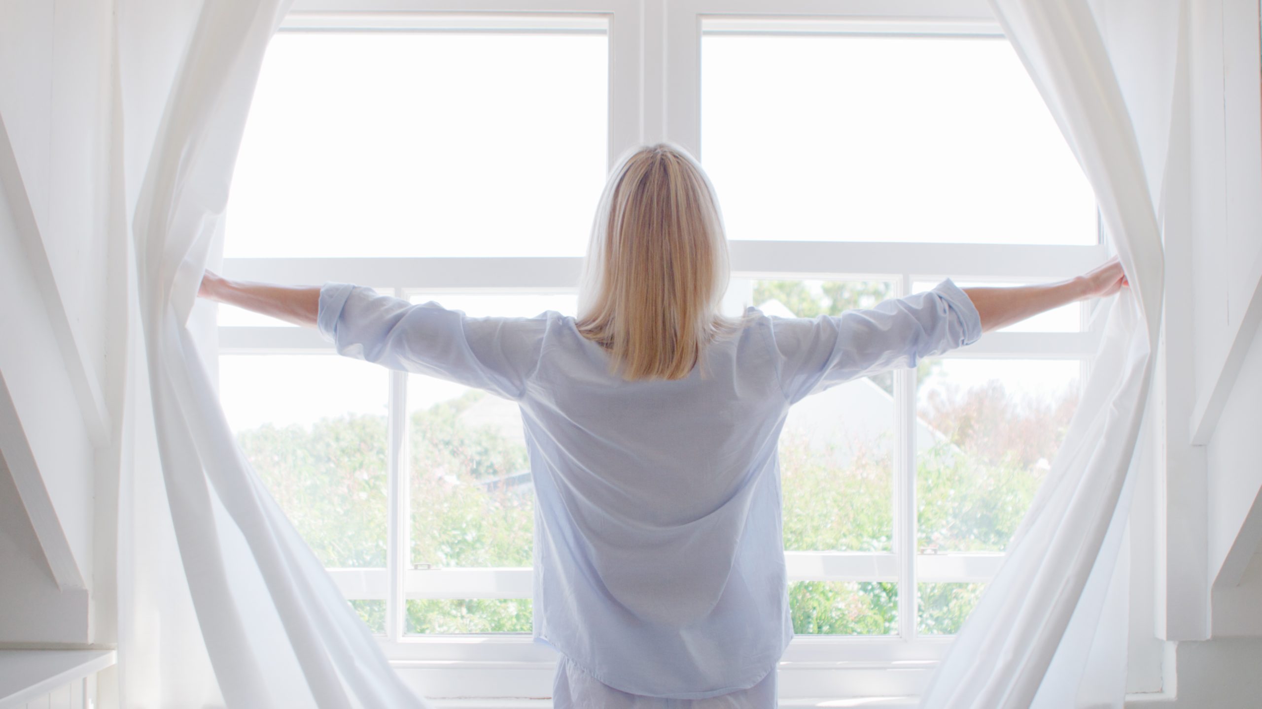 Woman Opening Curtains noise cancelling windows